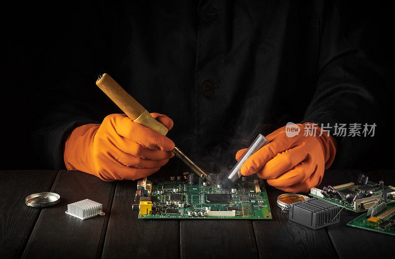 电子制造服务，电子板手工焊接。工头在车间里修理电脑或电子设备。