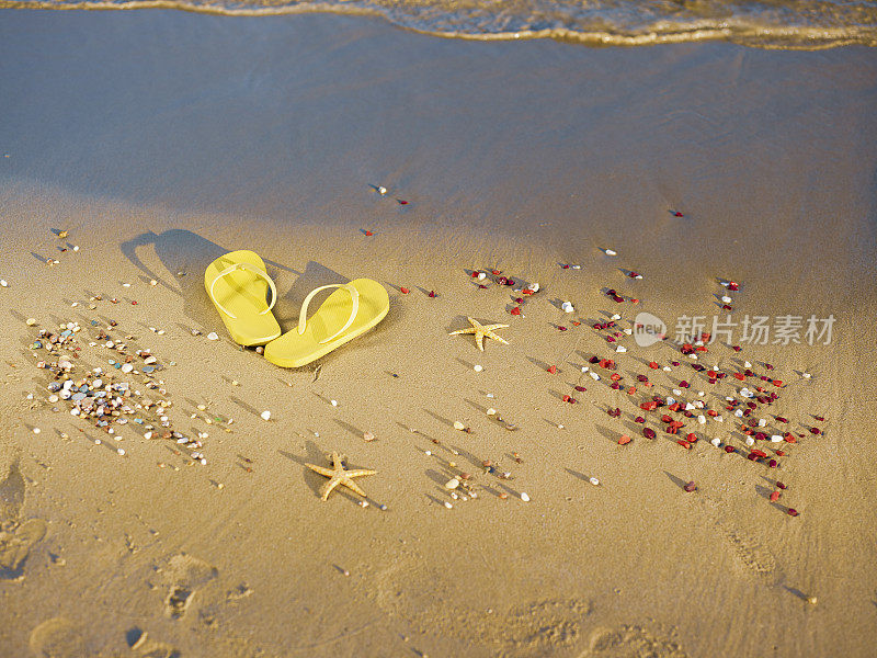 黄色的沙滩拖鞋站在沙滩上。