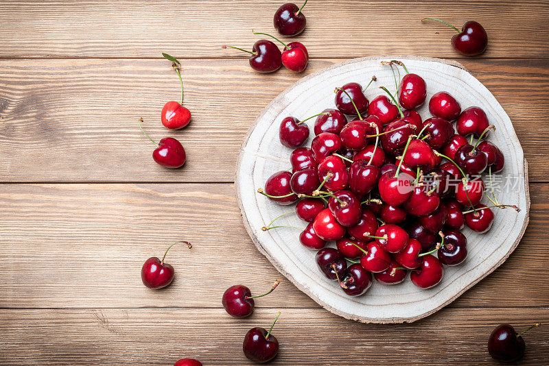 木质底座上的一套浓郁健康的红樱桃。富含维生素的水果是健康的饮食
