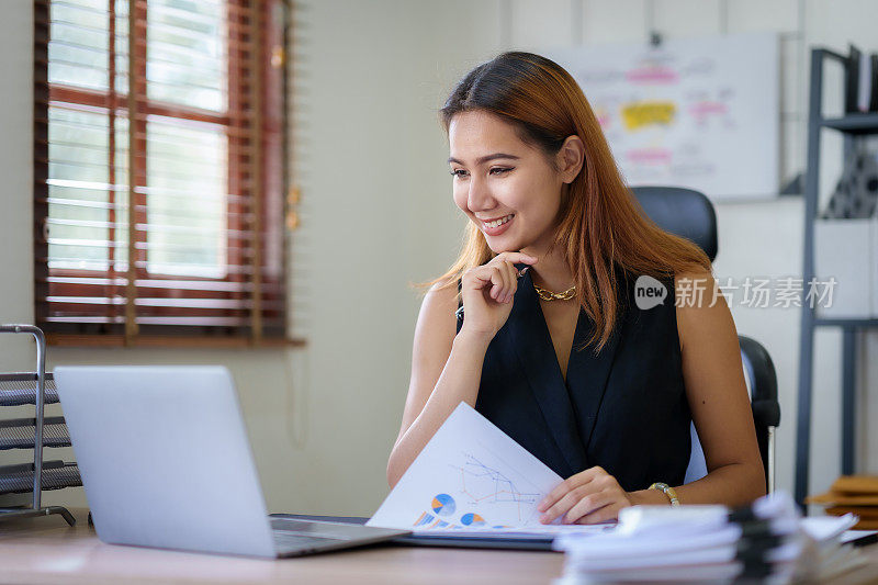 年轻的亚洲女商人，喜欢在办公室工作，桌子上有很多文件。
