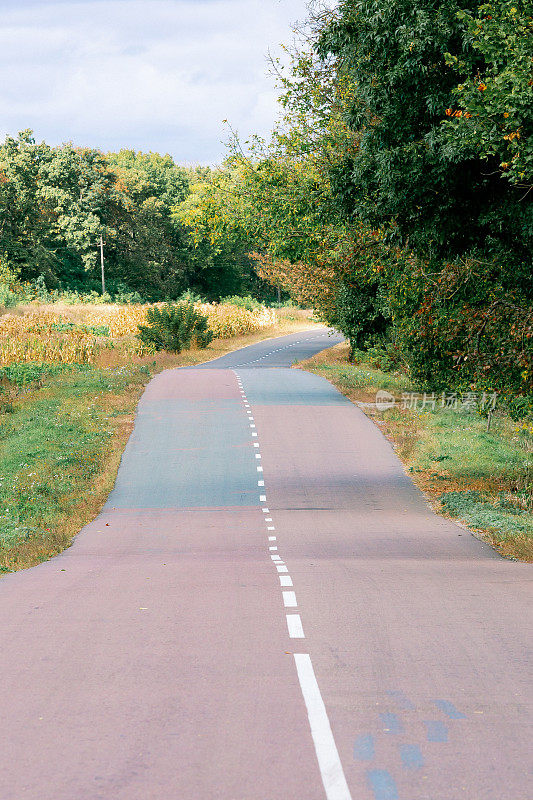 起伏不平的柏油路。前面是一条长长的路，弯弯曲曲的白线延伸到远处。