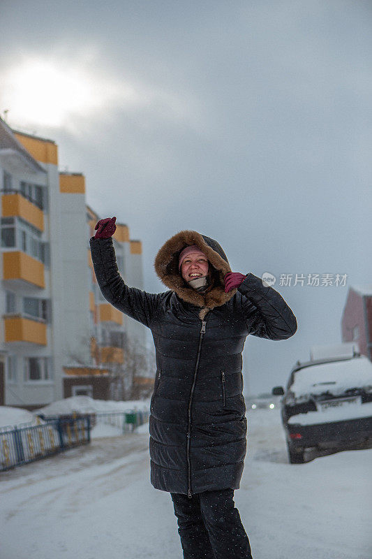 冬天来了，大暴雪来了。道路上有大雪，能见度低。妇女在危险的天气里缓慢而艰难地行走。大自然的大灾难。城市人的生活理念是暴风雪。