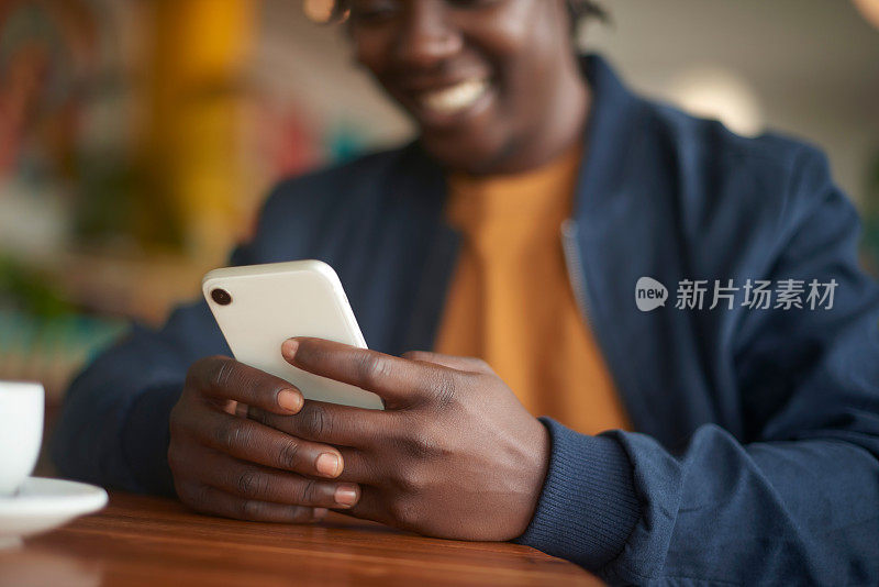 手机、手和黑人在社交媒体、手机应用程序或咖啡馆上网的特写。科技，研究和非洲男性在咖啡店用手机打短信。