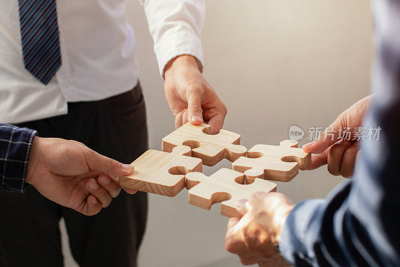 团队合作和伙伴关系的概念。商务人士在办公室里连接拼图。团队合作、团结、志愿、成功、战略。商业创意由拼图合并而成。