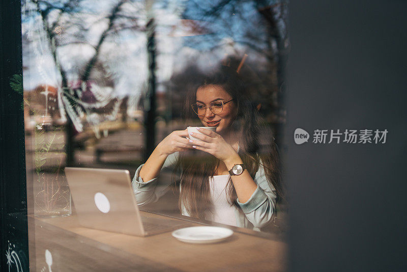 一位年轻女子在咖啡店使用她的笔记本电脑。