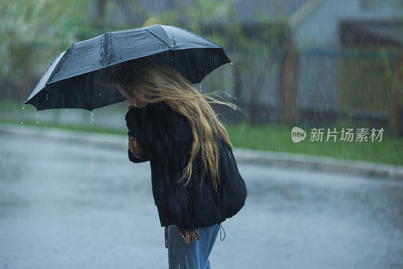 伞下的金发女人。暴风雨天气。暴雨