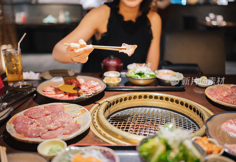 在一家日本餐馆里，亚洲Z世代的手在用竹炭烧烤烧肉串烤和和牛肉