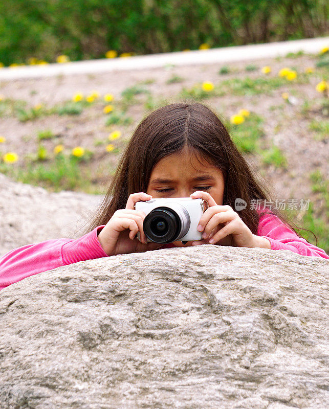 女孩拿着相机在岩石上拍照
