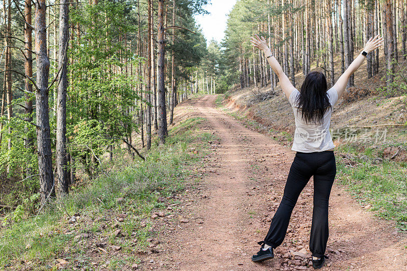 快乐的女跑步者正在森林里阳光明媚的小路上享受慢跑或越野跑。