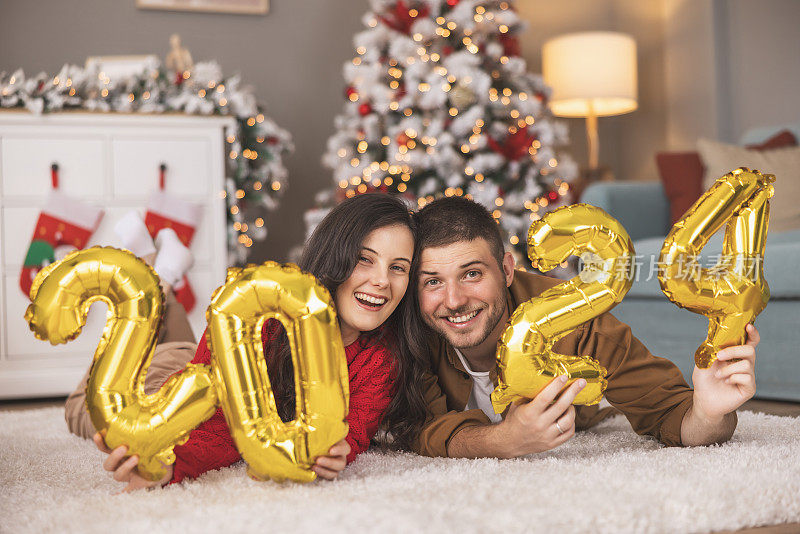一对夫妇手持2024气球，代表即将到来的新年