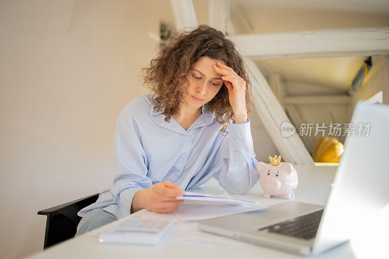 年轻女子使用计算器，同时通过账单和家庭财务