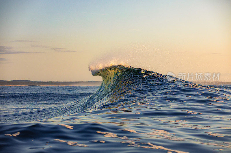 光滑弯曲的波浪在海洋与金色的天空黄昏