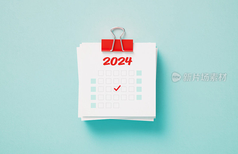 把2024年日历贴在蓝色背景上，用红色回形针夹住