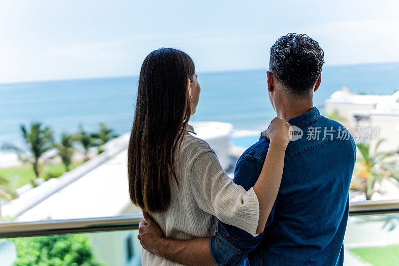 一对夫妇在酒店阳台上看风景的后视图