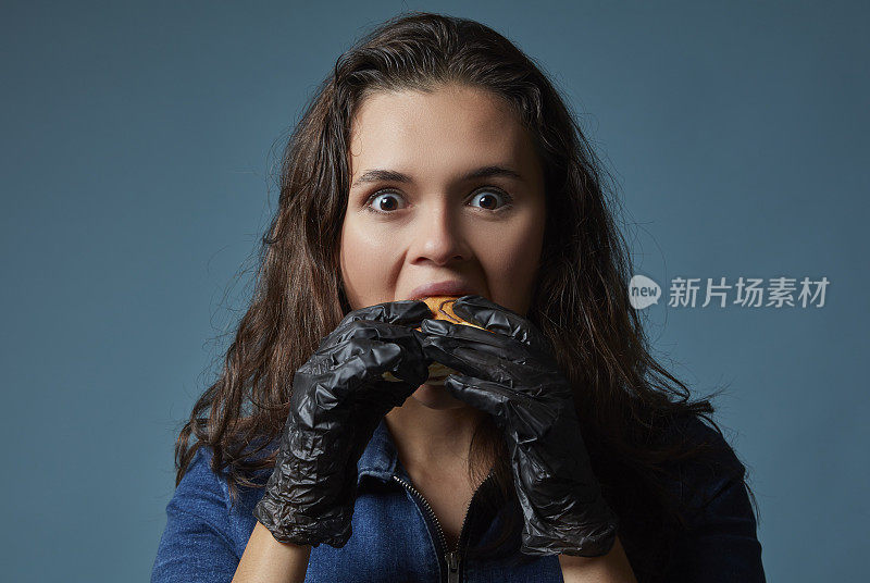 戴着黑色手套的年轻女子正在津津有味地吃蛋糕。