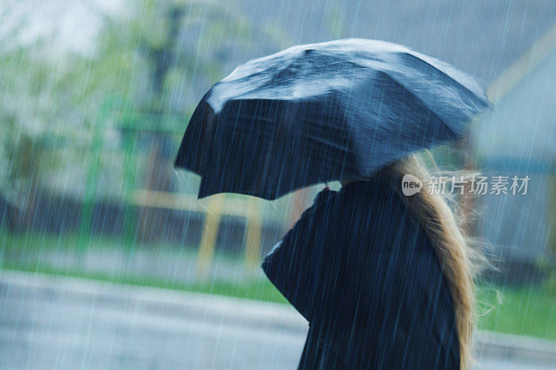 伞下的金发女人。暴风雨天气。暴雨