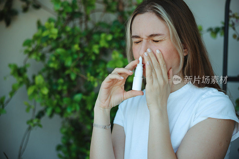 一名妇女得了流感，她正在使用鼻腔喷雾剂来帮助自己。