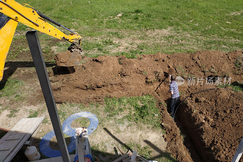 在挖好的沟渠上布线电缆，为地面上的房屋供电。