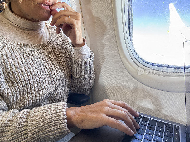 旅游和科技。我坐飞机上班。中年女商人坐在飞机上用笔记本电脑工作。