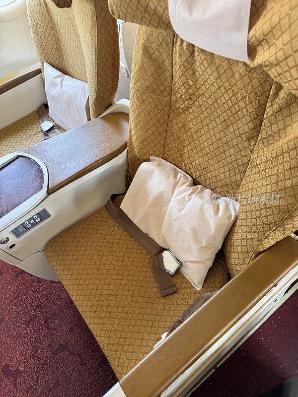 飞机内部特写，商务舱高级经济舱有额外的腿部空间，金色座椅，安全带躺在座位上，靠垫，抬高视野