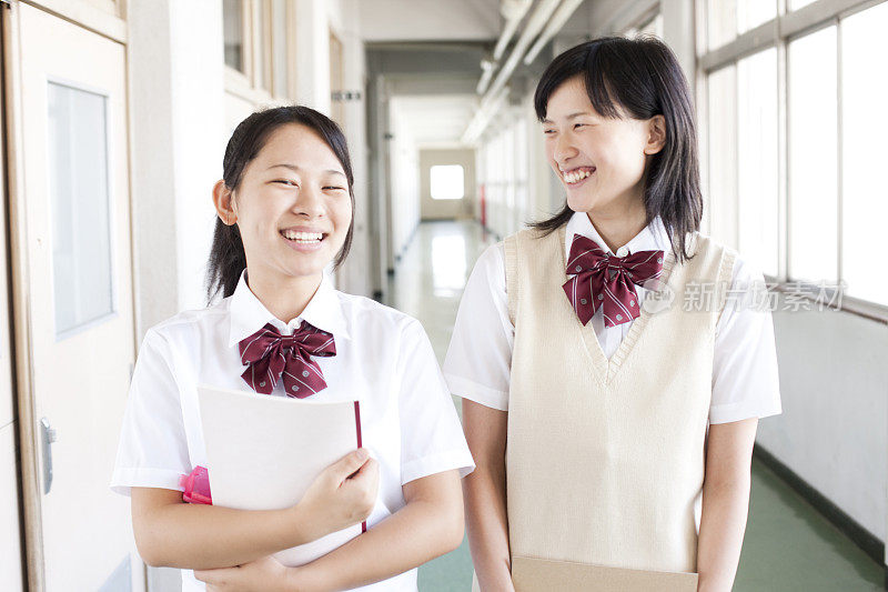 两名日本女学生微笑着走在学校走廊上