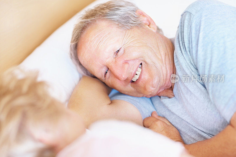 面带微笑的老人躺在床上的一个女人旁边