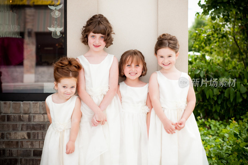四个快乐的花童穿着礼服站在一起