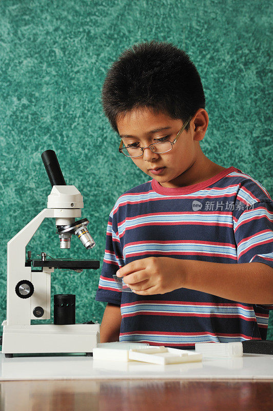 9岁的小男孩用显微镜学习