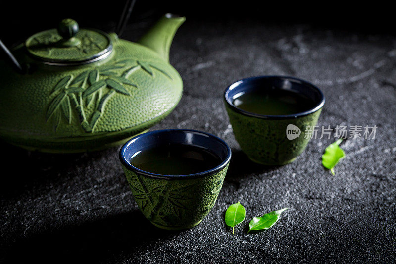 绿茶，茶壶和茶杯放在黑岩上