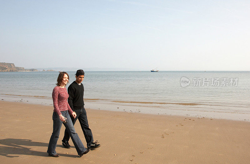 一对情侣在海滩上手拉手散步