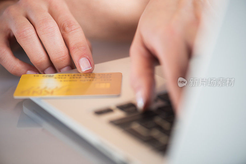 女性的手使用笔记本电脑在网上购物的特写