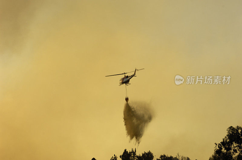 直升机在失控的野火上洒水