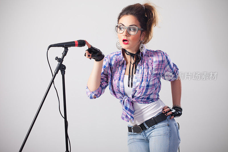 怪异的女歌手戴着眼镜碰着话筒