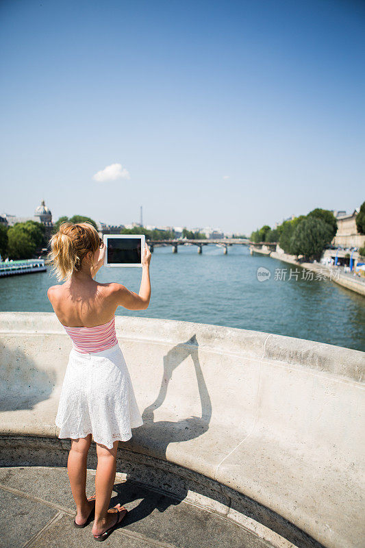 一名年轻女子在巴黎用平板电脑拍照