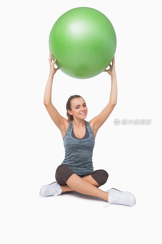 运动的年轻女子举起一个绿色的健身球