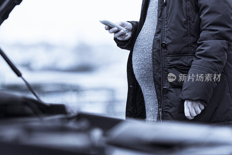 一个孕妇站在一辆破车旁