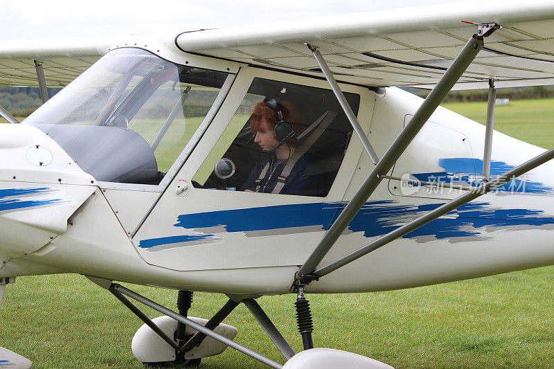 一个十几岁的男孩在飞机驾驶舱里，在机场上飞行课