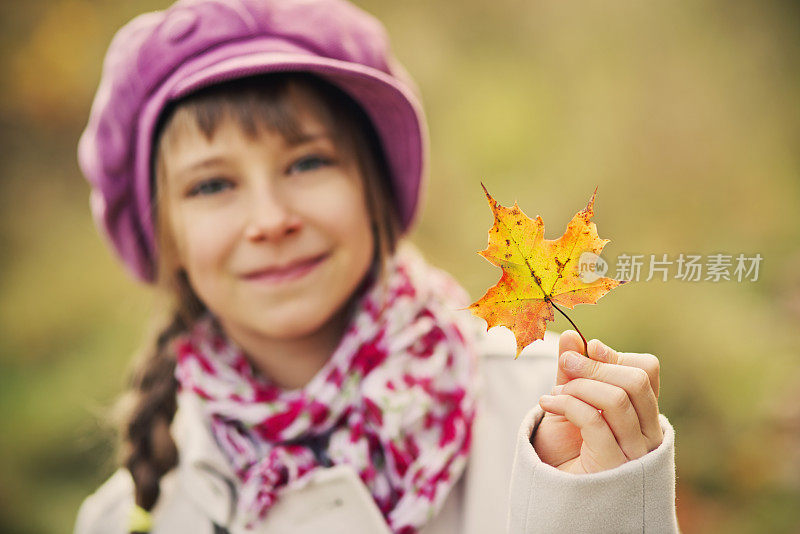 一个小女孩拿着一片秋叶的肖像