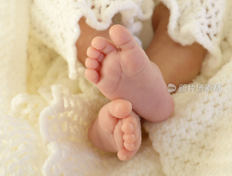 婴儿脚交叉近在白色毯子