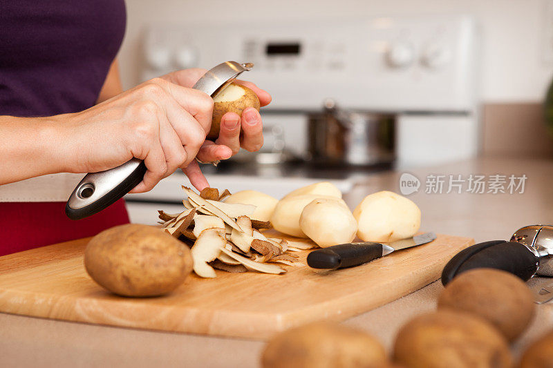 女人在厨房削土豆的彩色图像