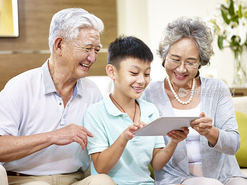 亚洲的祖父母和孙子一起使用数字平板电脑