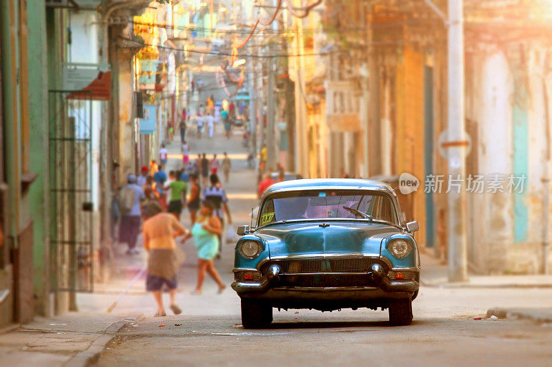 古巴哈瓦那的街头生活，前景是一辆老旧的美国出租车
