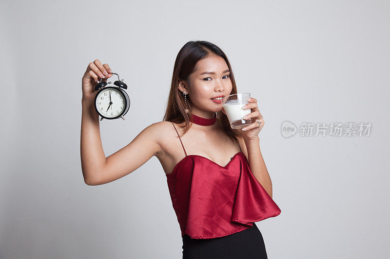 健康的亚洲女人喝牛奶抱钟。