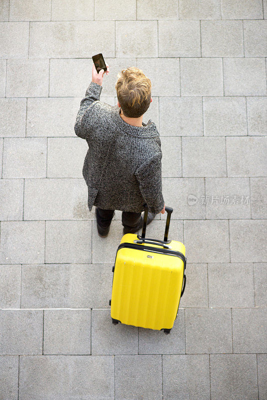 带着手机和行李箱的旅行男人