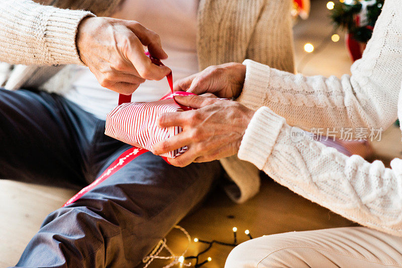 一对面目全非的老年夫妇在一起包装圣诞礼物。