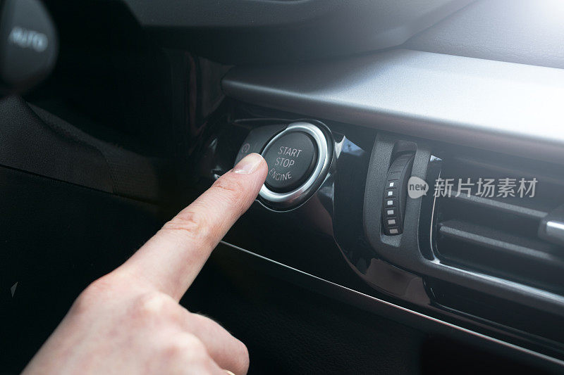 手指按按钮功能汽车发动机启动和停止在机动车预启动检查表的概念。现代汽车内部细节。柔和的灯光