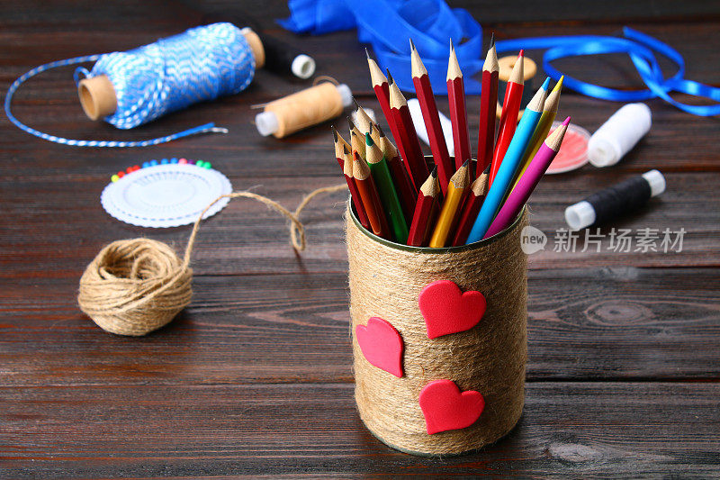 木制桌子上放着用绳子包着心形的铅笔。手工制作的。