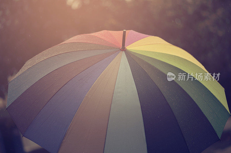 特写雨伞在秋雨霏霏的日子里用彩虹的色彩，模糊对焦