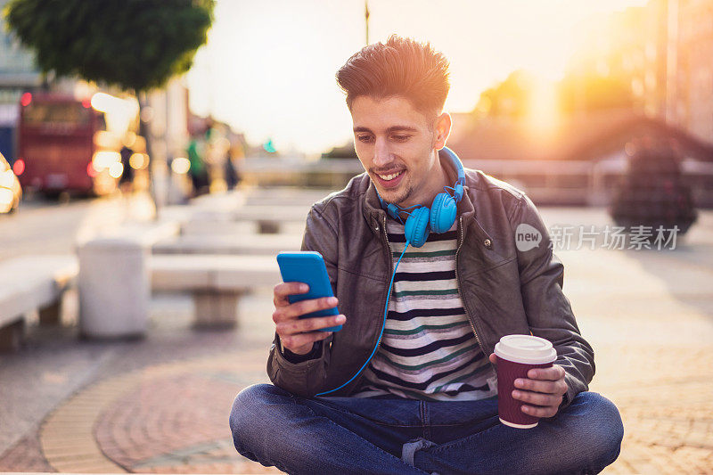年轻男性在城市的户外用手机发短信