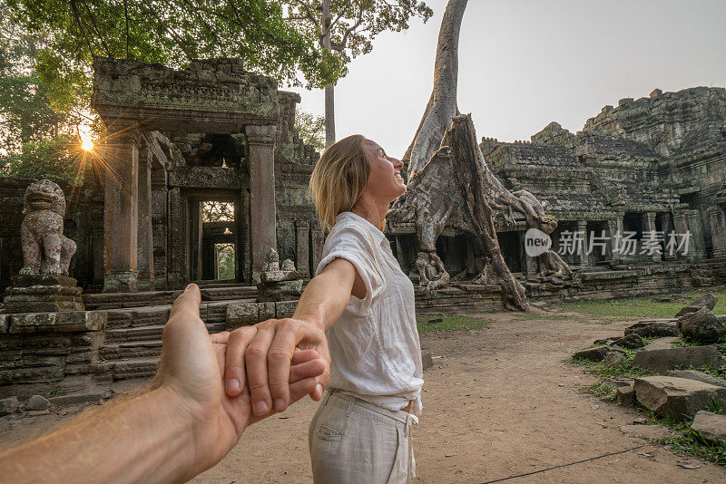跟着我去概念，女孩牵着男朋友的手带领他跟着去柬埔寨的古庙。人们旅行的幻想情侣概念
